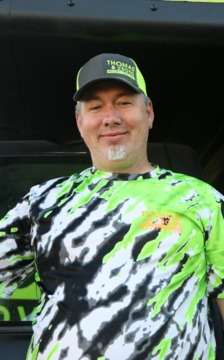 A man in green and black shirt wearing a hat.