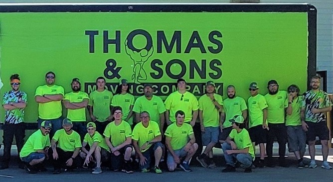 A group of men in front of a thomas & sons sign.
