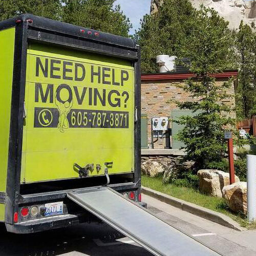 A moving truck with the back of it has a ramp on its side.